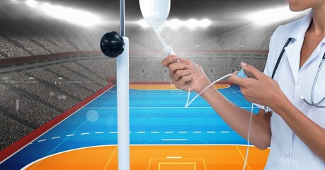 Female health worker regulating the intravenous drip against sports field with copy space