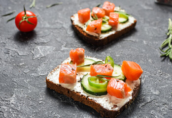 Healthy toasts with rye bread with cream cheese, salmon, fresh cucumber and sesame seeds.