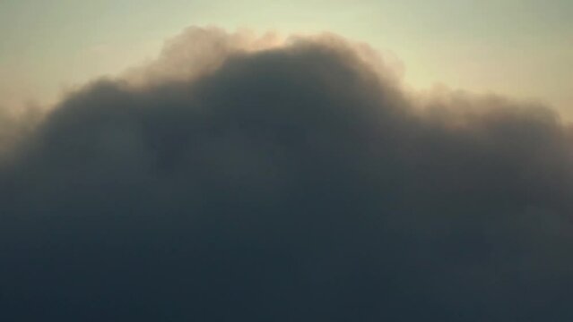 Cockpit view: fluffy cumulus clouds and sun - Sun above the clouds. Sun behind a dark heavy cloud: dawn high in the sky - Cloud motion against background of the sun and sky.