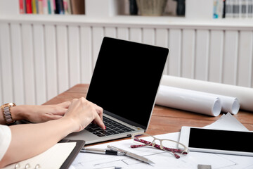 Hands of a woman engineer or architect working on laptop computer in office.