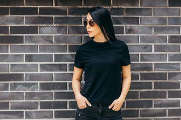Stylish brunette asian girl wearing black t-shirt and sunglasses posing against street , urban clothing style. Street photography