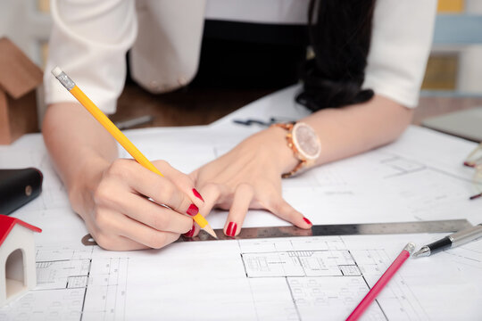 Female Architect working with pencil and ruler on blueprint. Architect engineer contractor design working drawing sketch plan blueprint and making architectural construction house building.