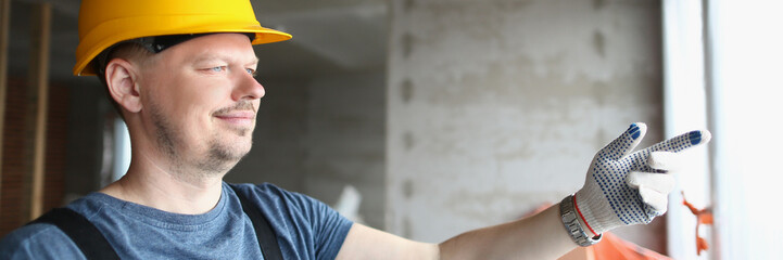 Foreman holding building plan and pointing outside window to look at business complex