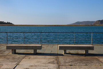 Fototapeta na wymiar Two stone benches in front of a estuary near the sea