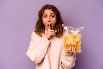 Young caucasian woman holding a bag of chips isolated on purple background keeping a secret or asking for silence.