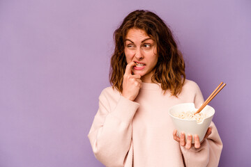 Young caucasian woman eating noodles isolated on purple background relaxed thinking about something looking at a copy space.