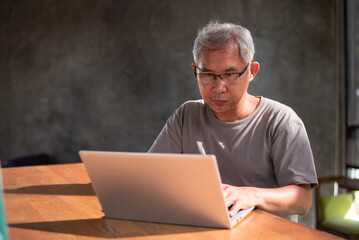 Asian senior man using laptop to do business in the home