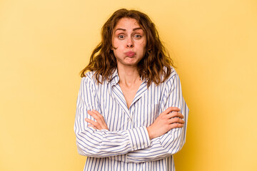 Young caucasian woman isolated on yellow background blows cheeks, has tired expression. Facial expression concept.