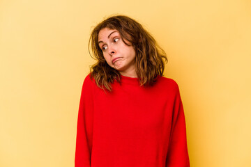 Young caucasian woman isolated on yellow background shrugs shoulders and open eyes confused.