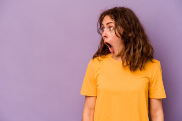 Young caucasian woman isolated on purple background being shocked because of something she has seen.