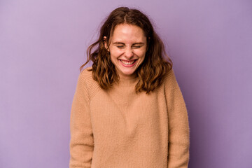 Fototapeta premium Young caucasian woman isolated on purple background laughs and closes eyes, feels relaxed and happy.