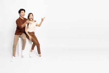 Young Asian couple smiling and pointing to empty copy space isolated on white background