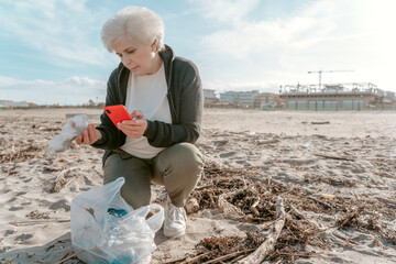 Concentrated lady taking pictures of garbage found on the beach
