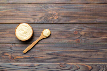Cheese sauce in wooden bowl with spoon on wood background. Top view with copy space