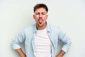 Fototapeta premium Young caucasian man isolated on white background funny and friendly sticking out tongue.