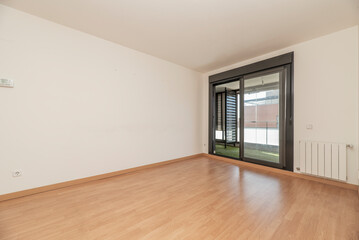 Empty living room with exit to a terrace with dark aluminum sliding doors and white aluminum radiator