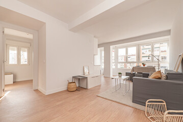 Living room and dining room with gray sofa, table with beige linen tablecloth and light wood flooring