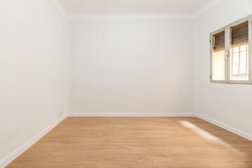 Empty room with aluminum window with shutter half up, wooden floorboards and plain white painted walls