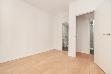 Empty room with two access doors to bathrooms, oak parquet floor and plain white painted walls