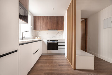 Front of a kitchen with white wooden furniture combined with wood-colored furniture and white...