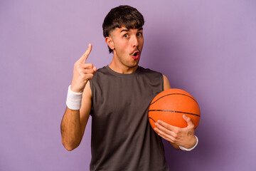 Young hispanic basketball player man isolated on purple background having an idea, inspiration concept.