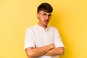 Young caucasian man isolated on yellow background suspicious, uncertain, examining you.