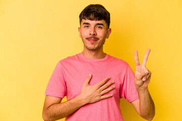 Young caucasian man isolated on yellow background taking an oath, putting hand on chest.