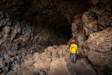 father and son hiking into dark cave at lava beds national monument