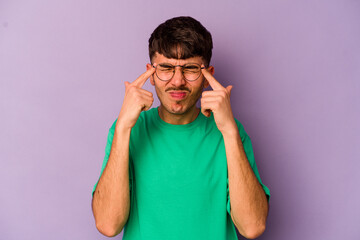 Young caucasian man isolated on purple background focused on a task, keeping forefingers pointing head.