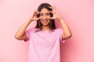 Young hispanic woman isolated on pink background keeping eyes opened to find a success opportunity.