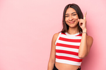 Young hispanic woman isolated on pink background showing number one with finger.