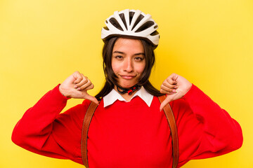 Young student hispanic woman wearing a bike helmet isolated on yellow background feels proud and self confident, example to follow.