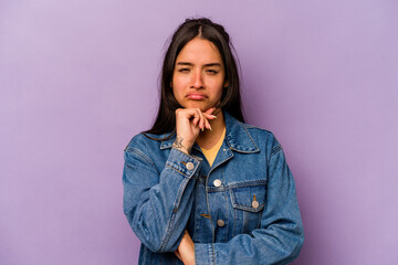 Young hispanic woman isolated on purple background thinking and looking up, being reflective, contemplating, having a fantasy.