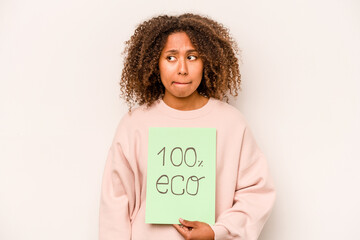 Young African American woman holding 100% eco placard isolated on white background confused, feels doubtful and unsure.