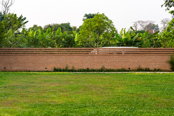 The brick wall, fence barrier is designed with a hole on top of wall in Asian style with garden...