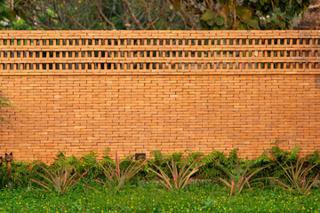 The brick wall, fence barrier is designed with a hole on top of wall in Asian style with garden...
