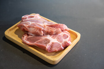Raw Pork is prepared for Cook, It is on wood plate on black granite kitchen counter tabletop, shot by studio light. Clipping Paths.