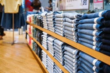 It was a brown shelf where clothes and blue jean pants of various grey tones were lined up in a clothing store where is the floor brown.