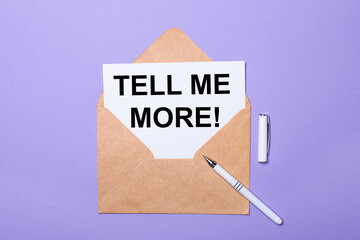 On a purple background, a white pen, a craft envelope and a white card with the text TELL ME MORE. View from above.