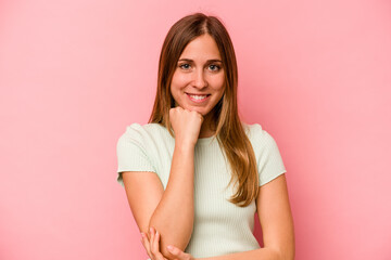 Fototapeta premium Young caucasian woman isolated on pink background smiling happy and confident, touching chin with hand.