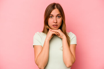 Young caucasian woman isolated on pink background praying for luck, amazed and opening mouth looking to front.