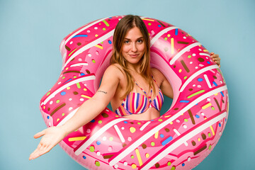 Young caucasian woman holding air mattress isolated on blue background