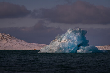 Fototapeta na wymiar 2022-05-10 A BLUE COLORED CHUNK OF FLOATING ICE IN THE OCEAN IN THE ARCTIC NEAR THE ISLAND OF SVALABRD NORWAY