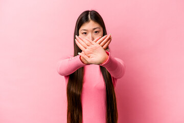 Young Chinese woman isolated on pink background doing a denial gesture
