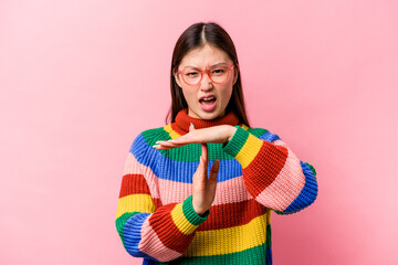 Young Chinese woman isolated on pink background showing a timeout gesture.