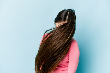 Young asian woman moving hair isolated on blue background