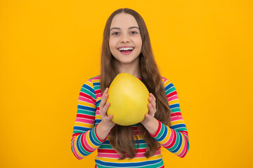 Summer fruits. Teenager child girl hold citrus fruit pummelo or pomelo, isolated on yellow background. Kid healthy eating.