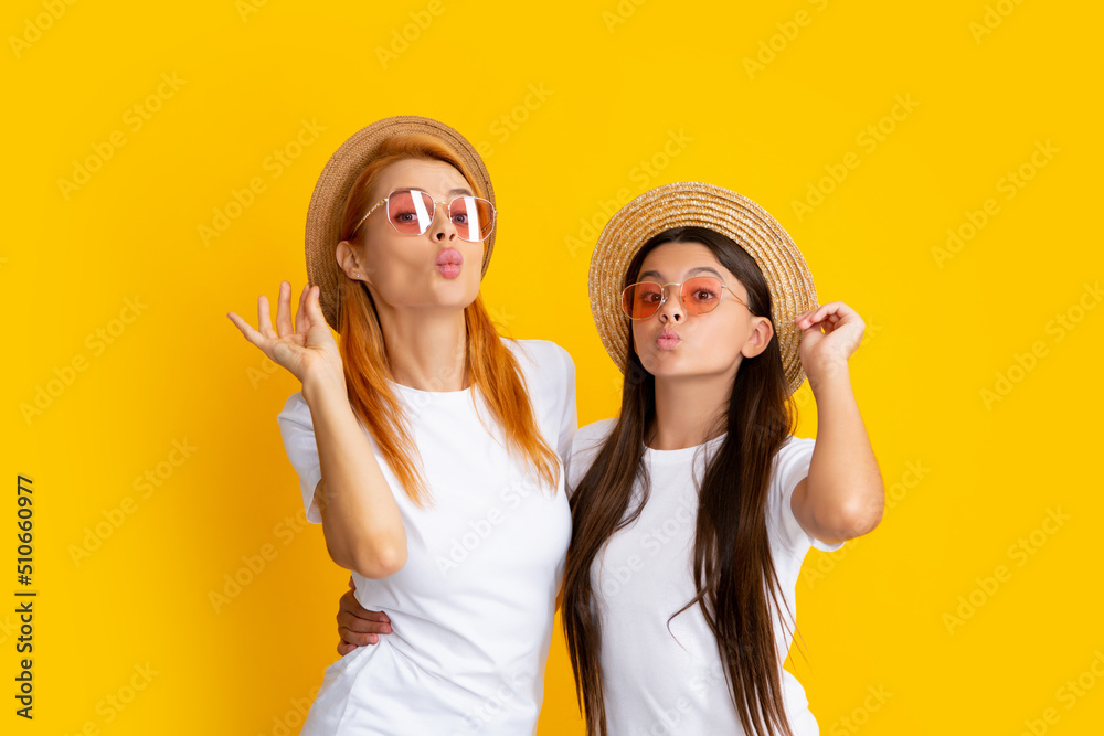 Sticker Romantic summer mood. Happy stylish mother and daughter posing at studio yellow background, wearing straw hat and sunglasses. Summer family portrait.