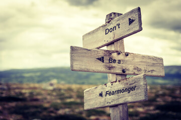 dont be a fearmonger text quote on wooden signpost outdoors in nature. Inflation, economy and finance concept.