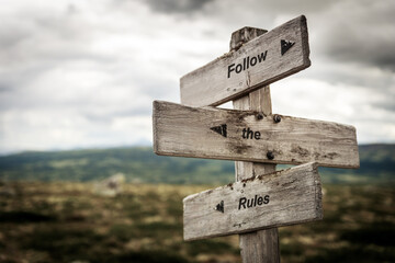 follow the rules text quote on wooden signpost outdoors in nature. Business and finance, law and education concept.